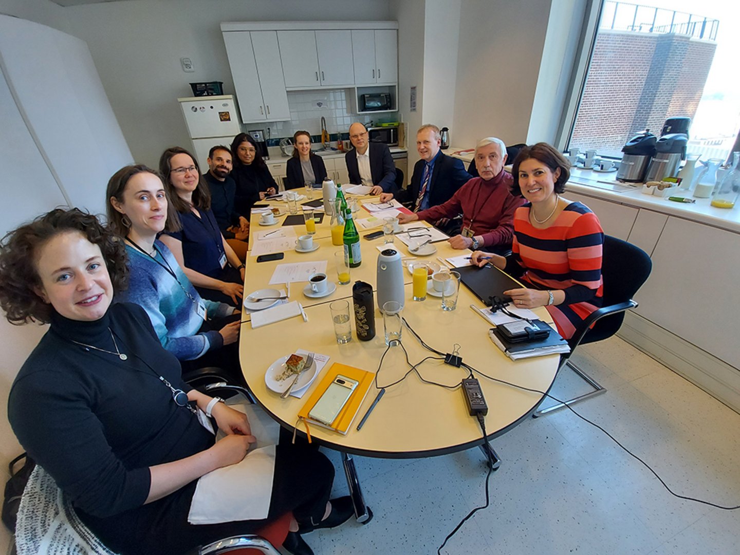 A group of people sitting around a conference table filled with notebooks and beverages