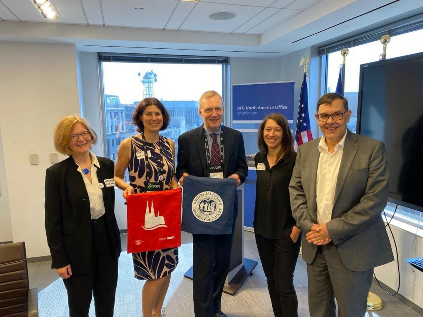 Five people posing for a picture with University of Cologne tote bags
