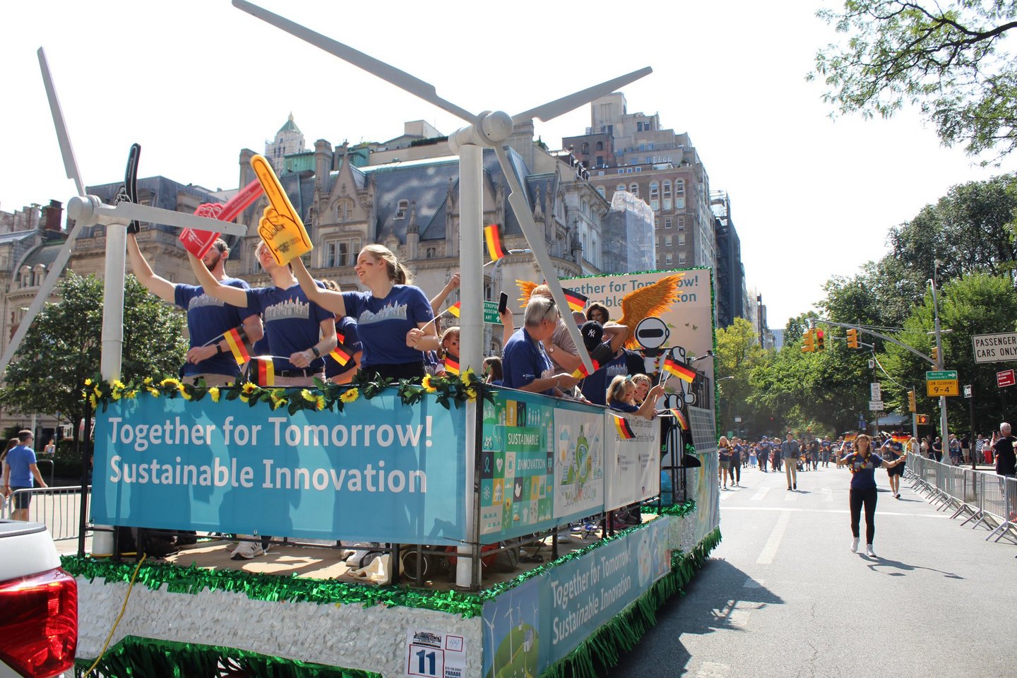 A parade float filled with people waving German flags and equipped with a banner reading Together for Tomorrow! Sustainable Innovation