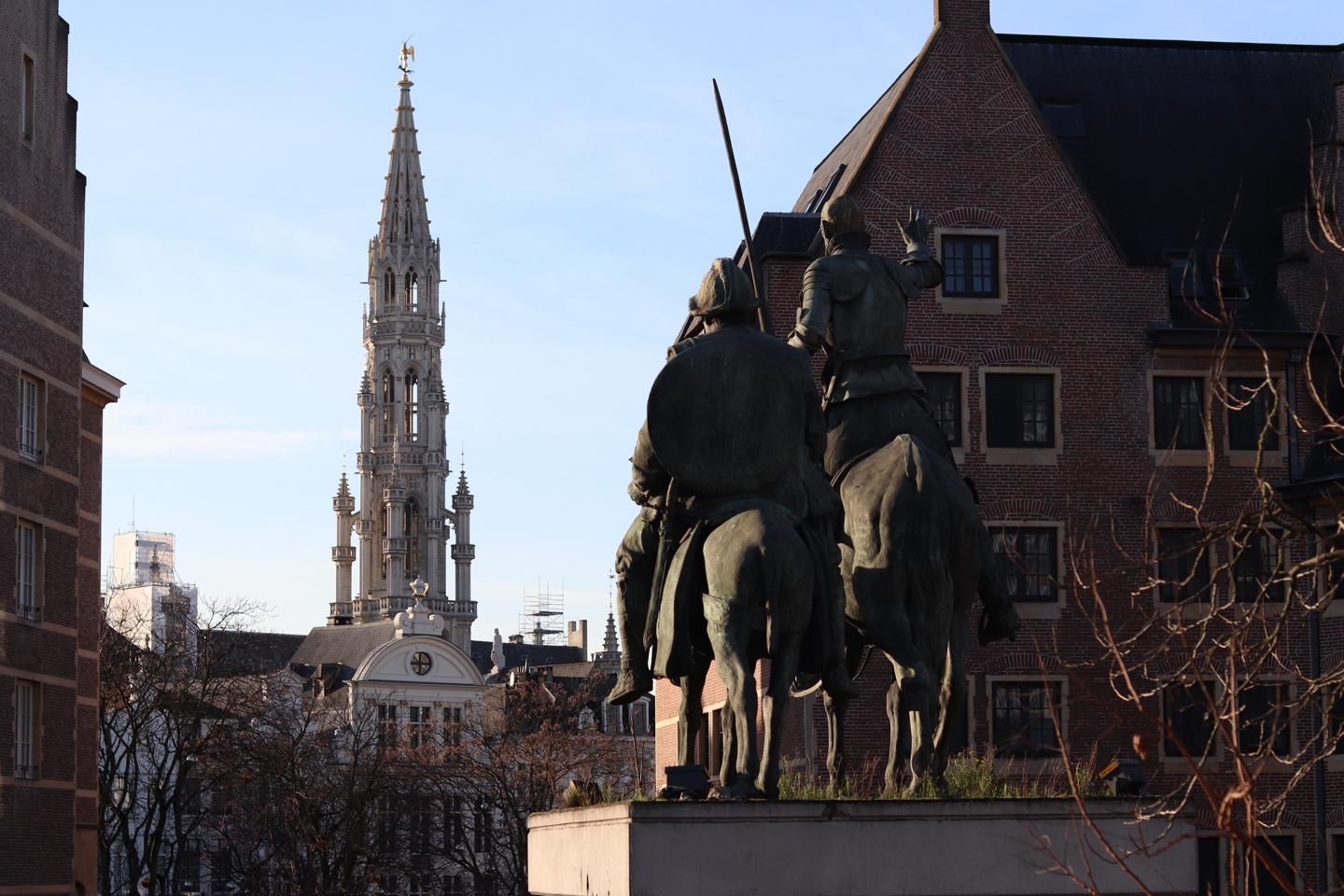 View on the tower of the grote markt and a statue of two people on horses.