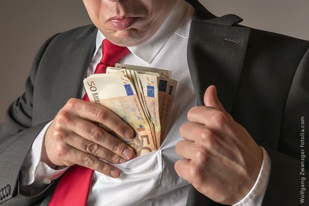 Mann steckt sich ein Bündel von 50-Euro-Scheinen in die Hemdtasche
