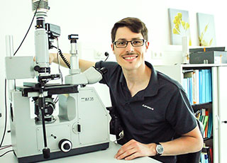 Dr. Hess neben einem Mikroskop